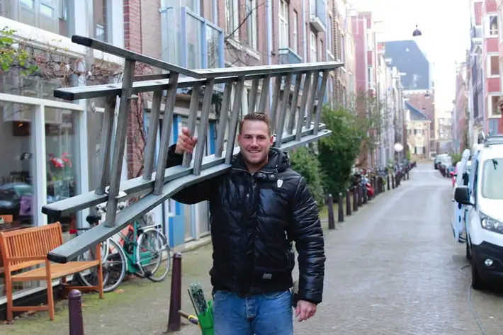 Eigenaar Boy Bolderman met een ladder in een Amsterdamse straat