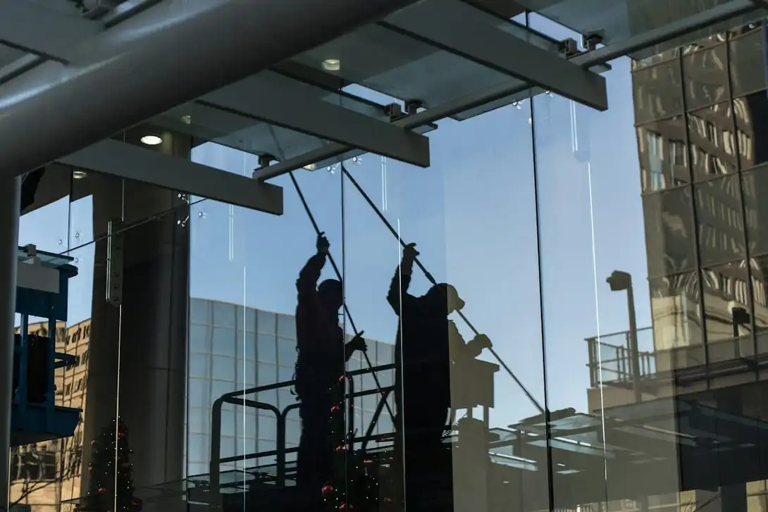 Glazenwassers op een hoogwerker wassen een glazen gevel