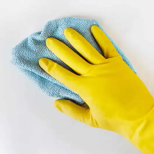 Gele schoonmaakhandschoen met een blauwe microvezeldoek